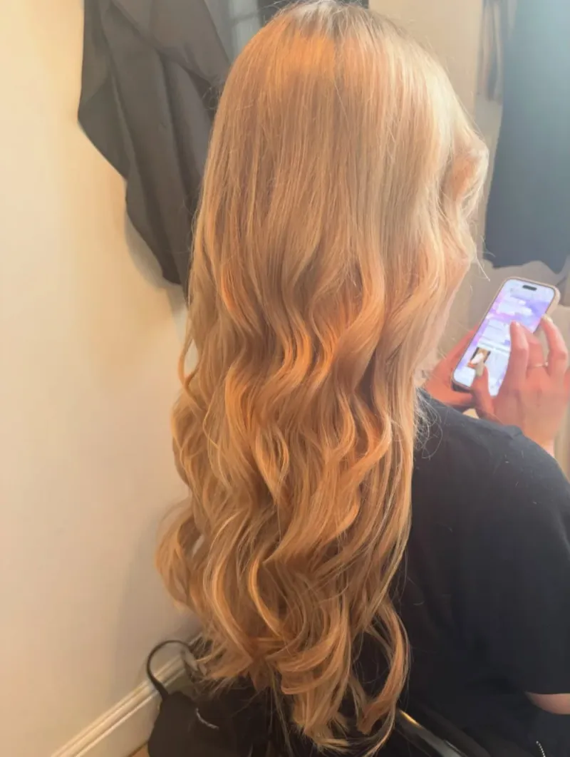 Long blonde hair styled into soft waves after an extension fitting